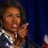 Virginia Lt. Gov. Winsome Earle-Sears speaks at a podium with American flags in the background and gestures by pointing her finger to the audience
