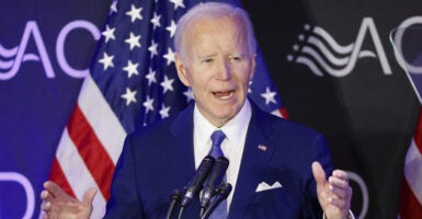 Former President Joe Biden at a microphone with a U.S. flag behind him